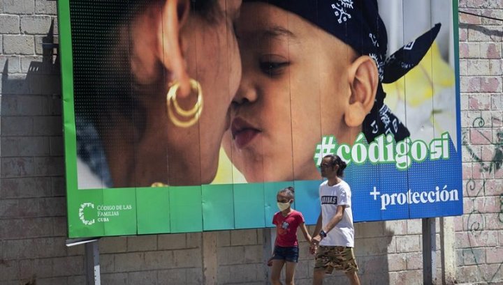 Un hombre y su hija pasan caminando frente a una valla que hace parte de la campaña por el SÍ en el referendo sobre el código de familia. Efe